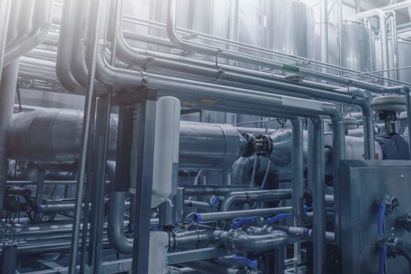 Die Fabrik verfügt über ein komplexes Netzwerk aus Metallrohren und Industriemaschinen, die von hellem Licht erhellt werden. Das System integriert das kommunale Spülverfahren effizient und sorgt so für optimale Leistung.