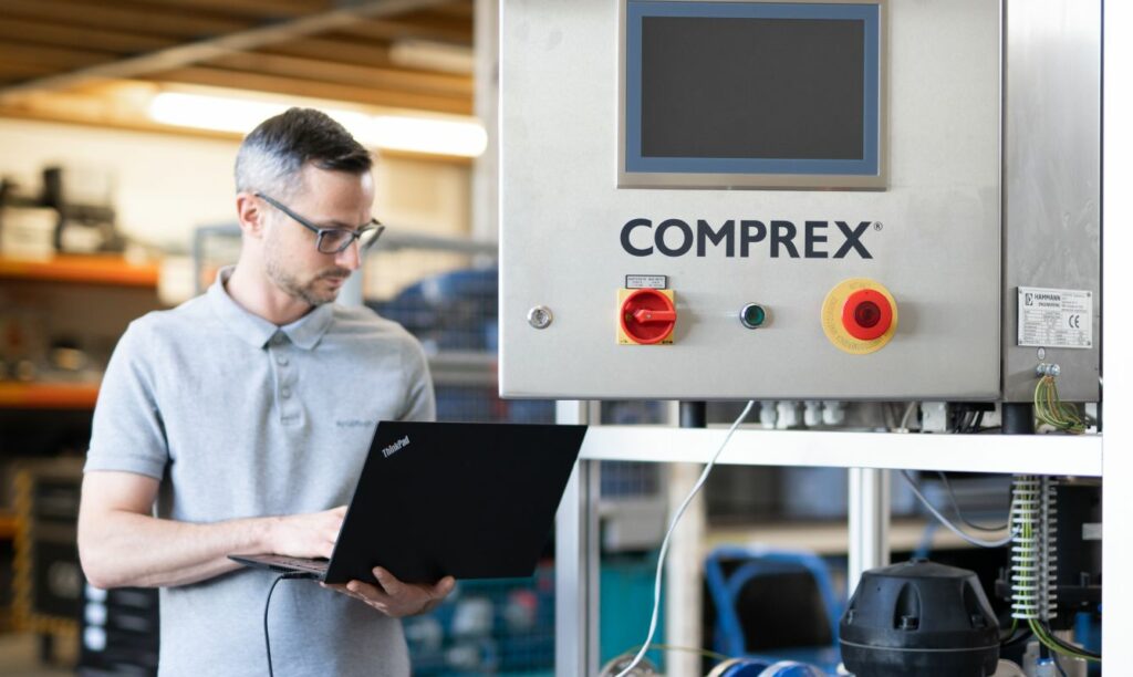 A SCU man using a laptop in a factory.