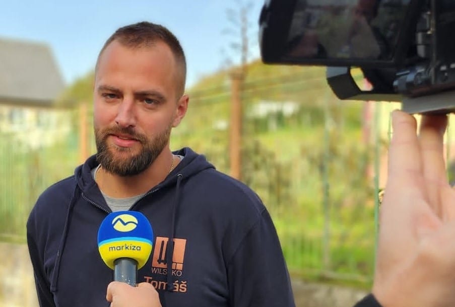 Ein Mann mit Bart hält selbstbewusst ein Mikrofon in der Hand und strahlt eine Aura von Charisma und Autorität aus.