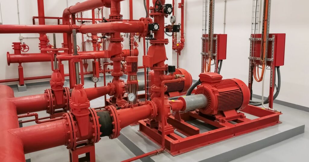 Rote Feuerwehrschläuche und -rohre in einem Raum für die Reinigung von Löschsystemen.