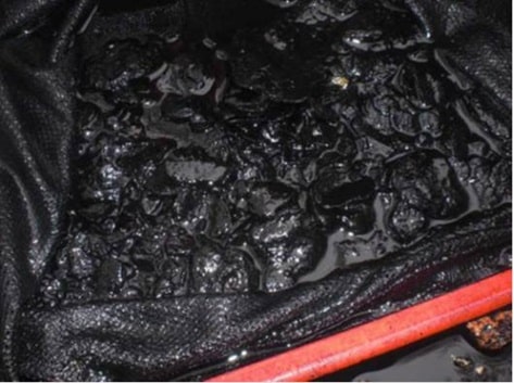 Ein Behälter, der mit einer zähflüssigen schwarzen Substanz und glänzenden schwarzen festen Objekten gefüllt ist, die teilweise in die Flüssigkeit eingetaucht sind und dazu bestimmt sind, Grobpartikel und Späne auszutragen.