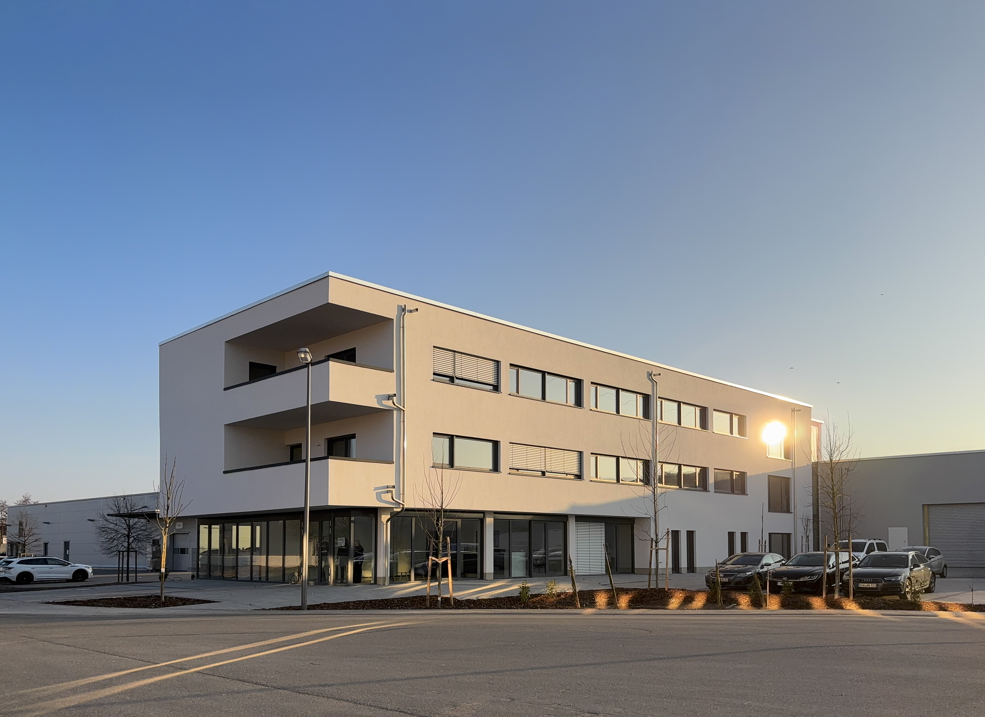 Modernes dreistöckiges Gebäude mit großen Fenstern und einem Parkplatz unter einem klaren blauen Himmel, das sein makelloses Äußeres zur Schau stellt und die Präzision widerspiegelt, die man von industriellen Rohrreinigungsdiensten erwartet.